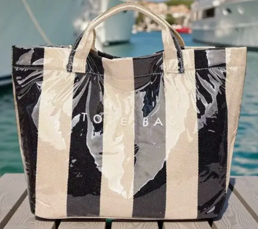 Clear coated Black and beige Striped tote bag with 'Tote Bag'  on a wooden surface with water and boats in the background
