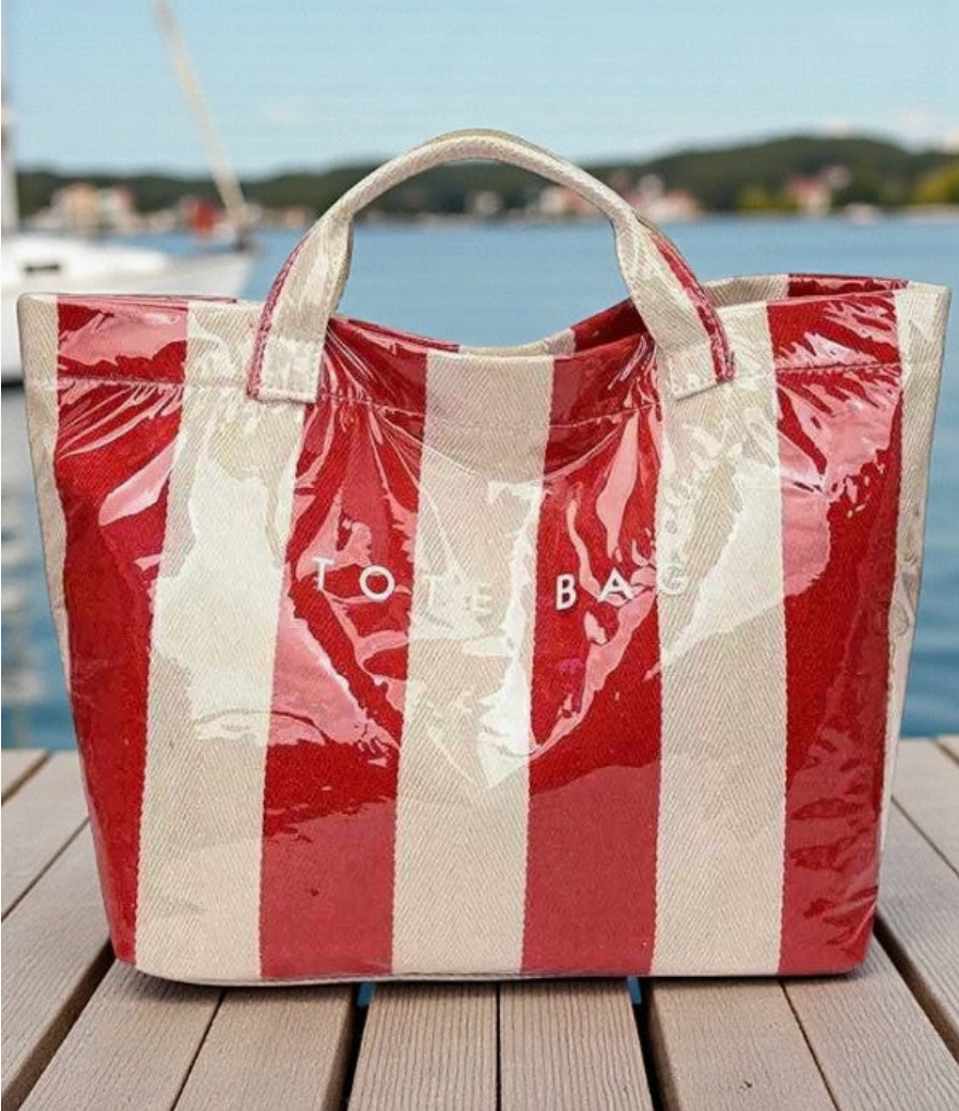 Clear coated Red and white striped tote bag on a wooden dock with water and sky in the background