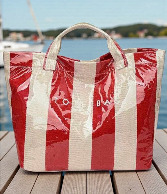 Clear coated Red and white striped tote bag on a wooden dock with water and sky in the background